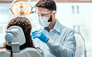 A dentist in full PPE examines a patient.